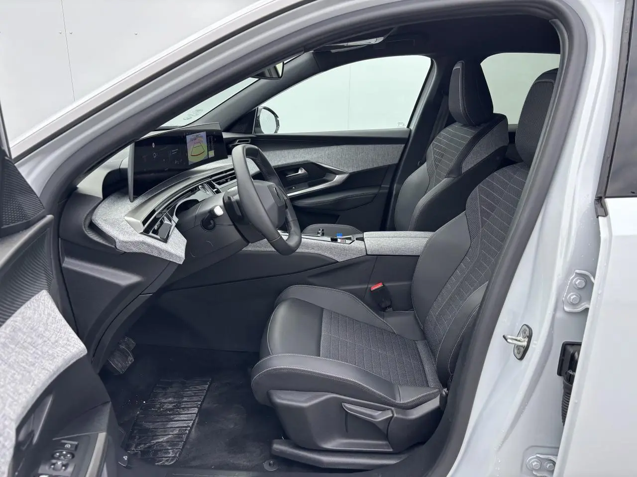 Intérieur avant droit du Peugeot 3008 blanc Okenite 2024 avec sellerie tissu gris et tableau de bord moderne.