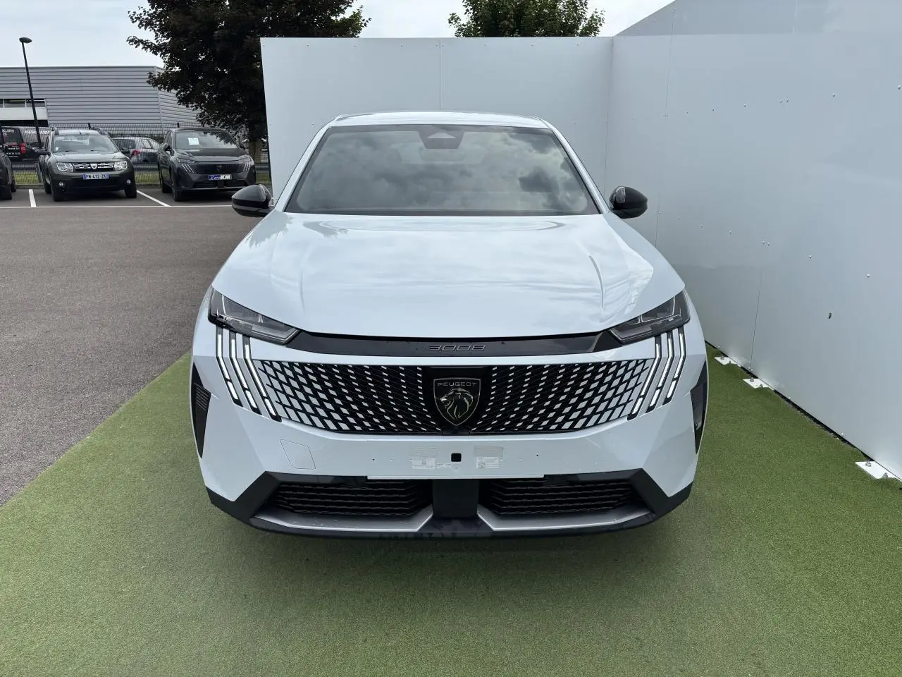 Vue avant du Peugeot 3008 blanc Okenite 2024 avec calandre noire à motif géométrique et feux LED griffés.
