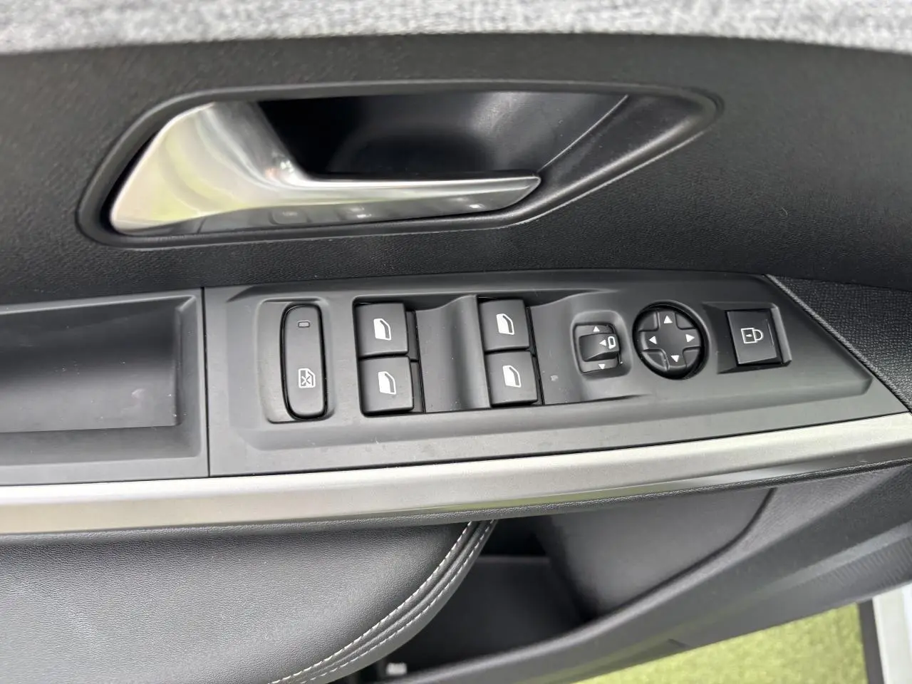 Gros plan sur la commande des vitres et rétroviseurs côté conducteur d'un Peugeot 3008 blanc Okenite 2024.
