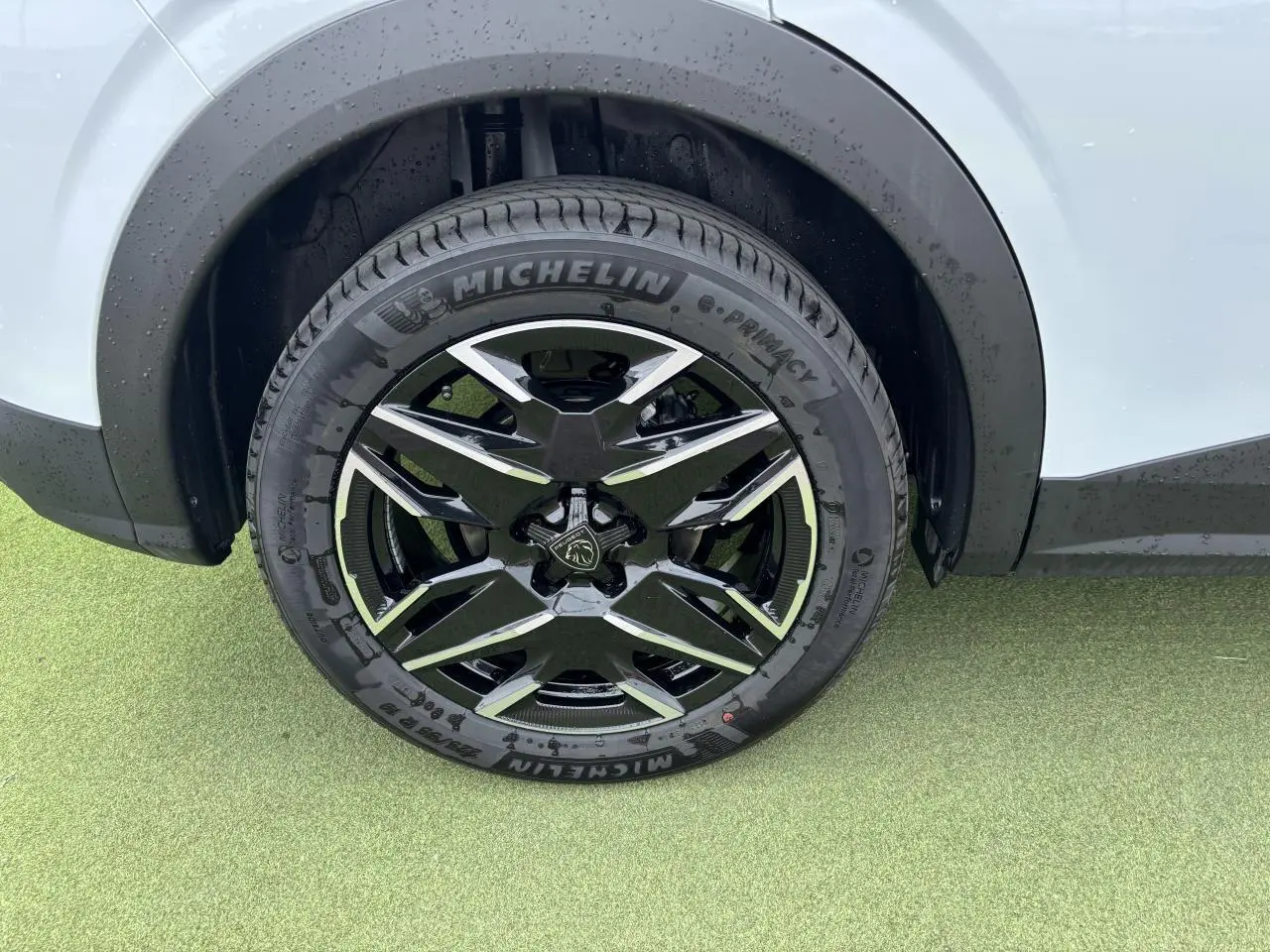 Gros plan sur la roue avant droite du Peugeot 3008 blanc Okenite avec jante alliage noire et diamantée 19 pouces.