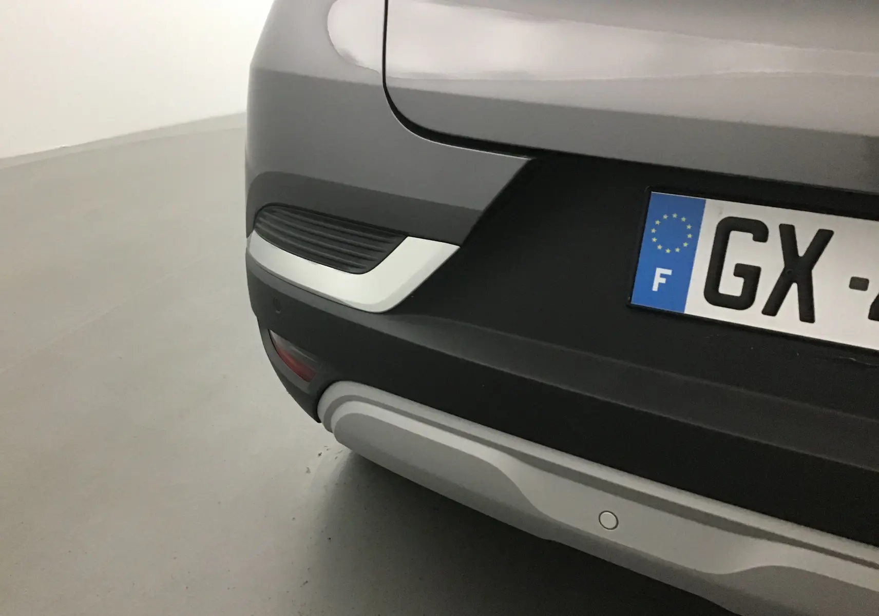 Gros plan sur le coin arrière droit gris cassiopée et noir du Renault Captur 2024 avec plaque d'immatriculation française.
