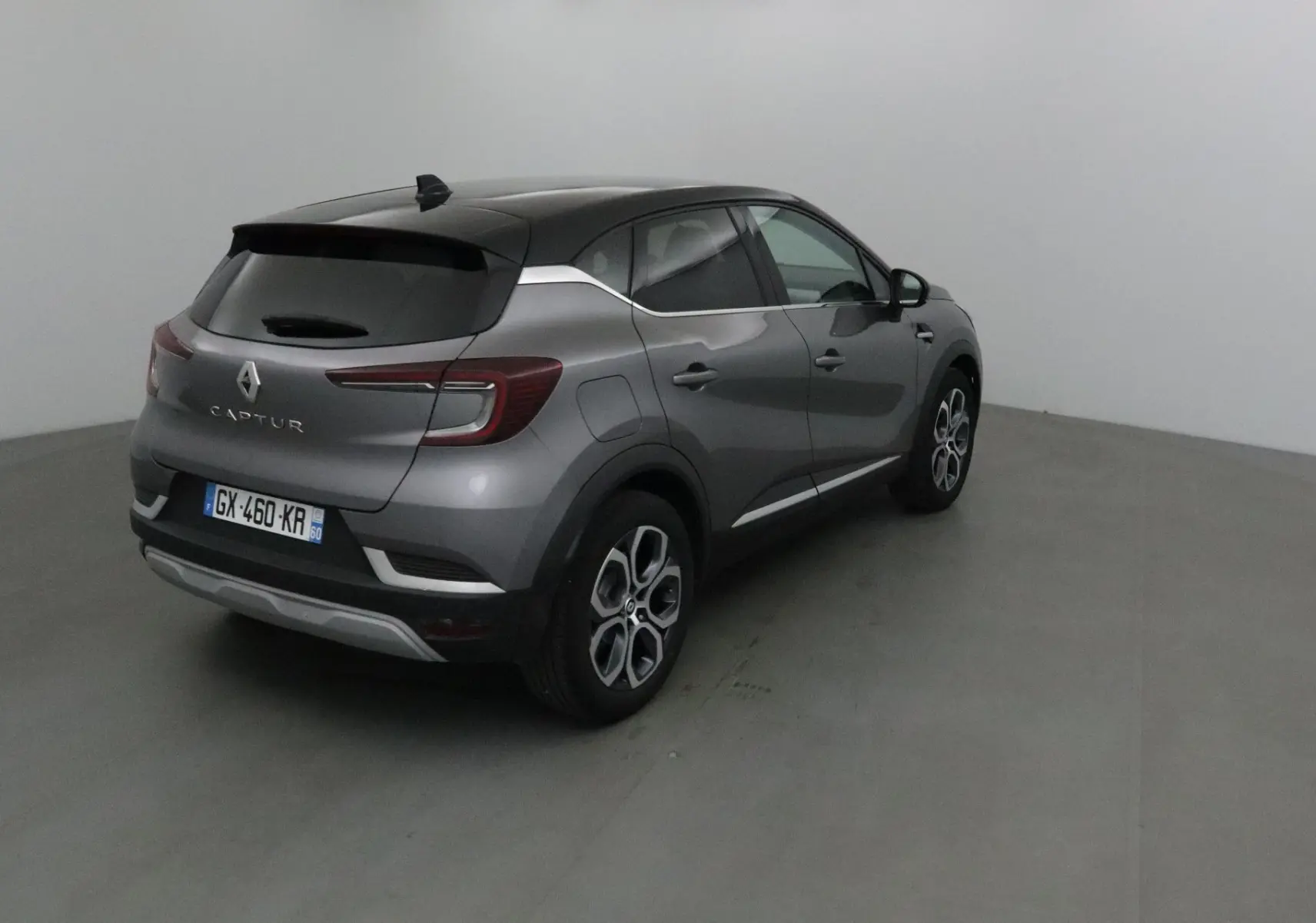Renault Captur gris Cassiopée et noir vu en 3/4 arrière droit, avec jantes 18 pouces et feux LED distinctifs.
