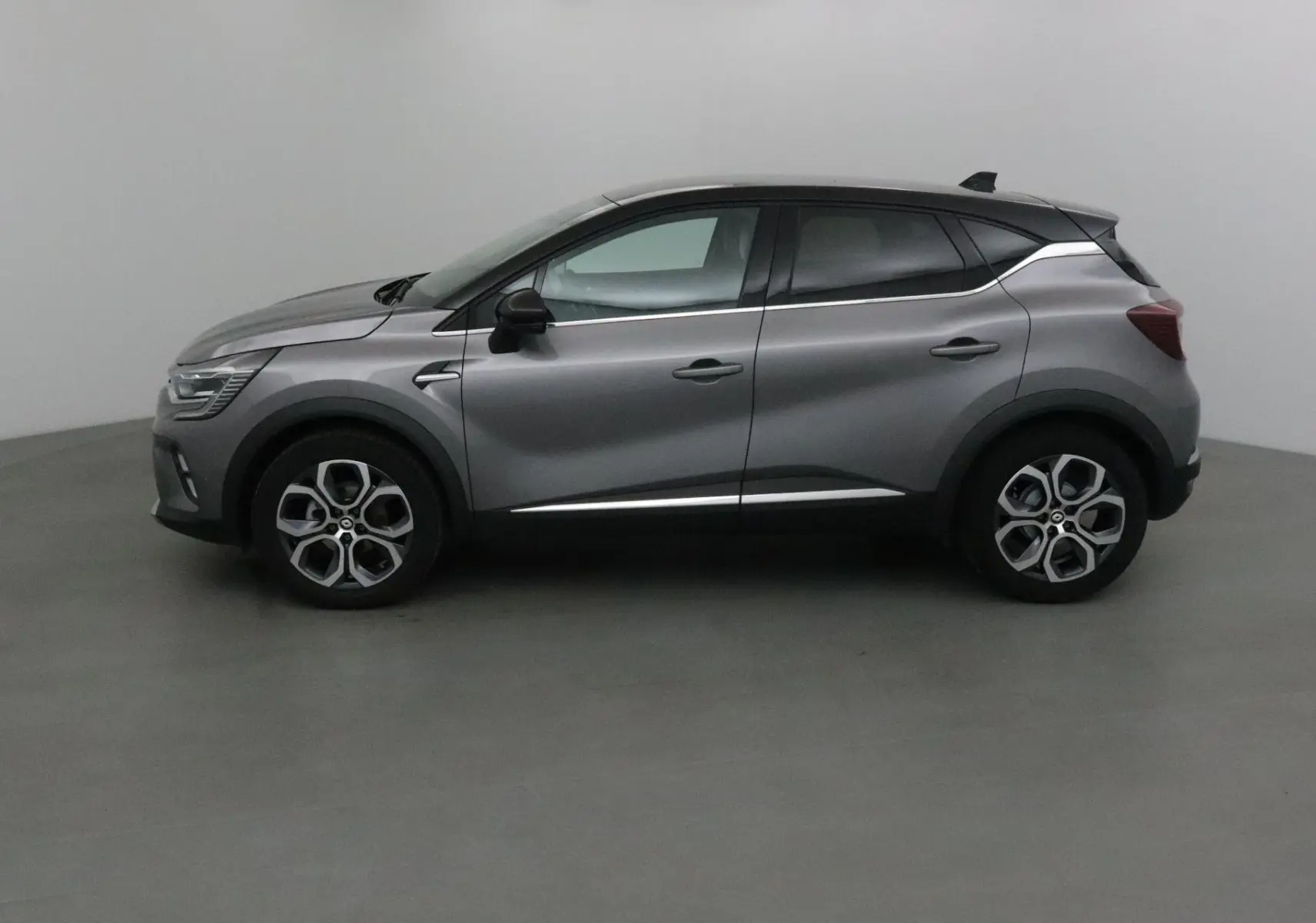 Profil latéral droit d'un Renault Captur 2024 gris Cassiopée avec toit noir et détails chromés.