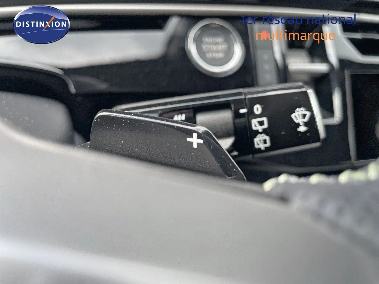 Gros plan sur la palette de changement de vitesse + du Peugeot 5008 Hybrid 136ch GT, intérieur noir et commandes au volant.