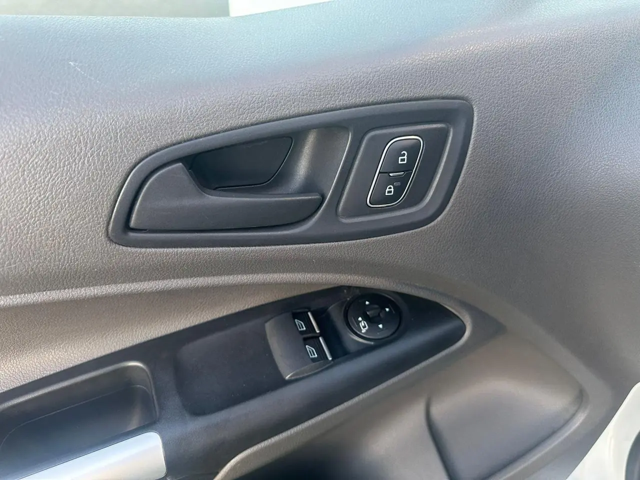 Gros plan sur la porte côté conducteur du Ford Transit Connect blanc, montrant les commandes de vitres et verrouillage.