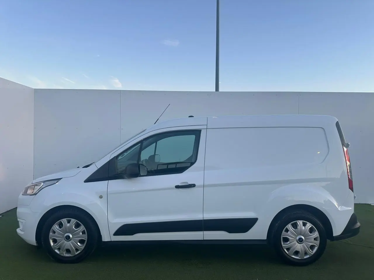 Profil côté gauche du fourgon blanc Ford Transit Connect 2019 avec porte latérale coulissante et protections noires.