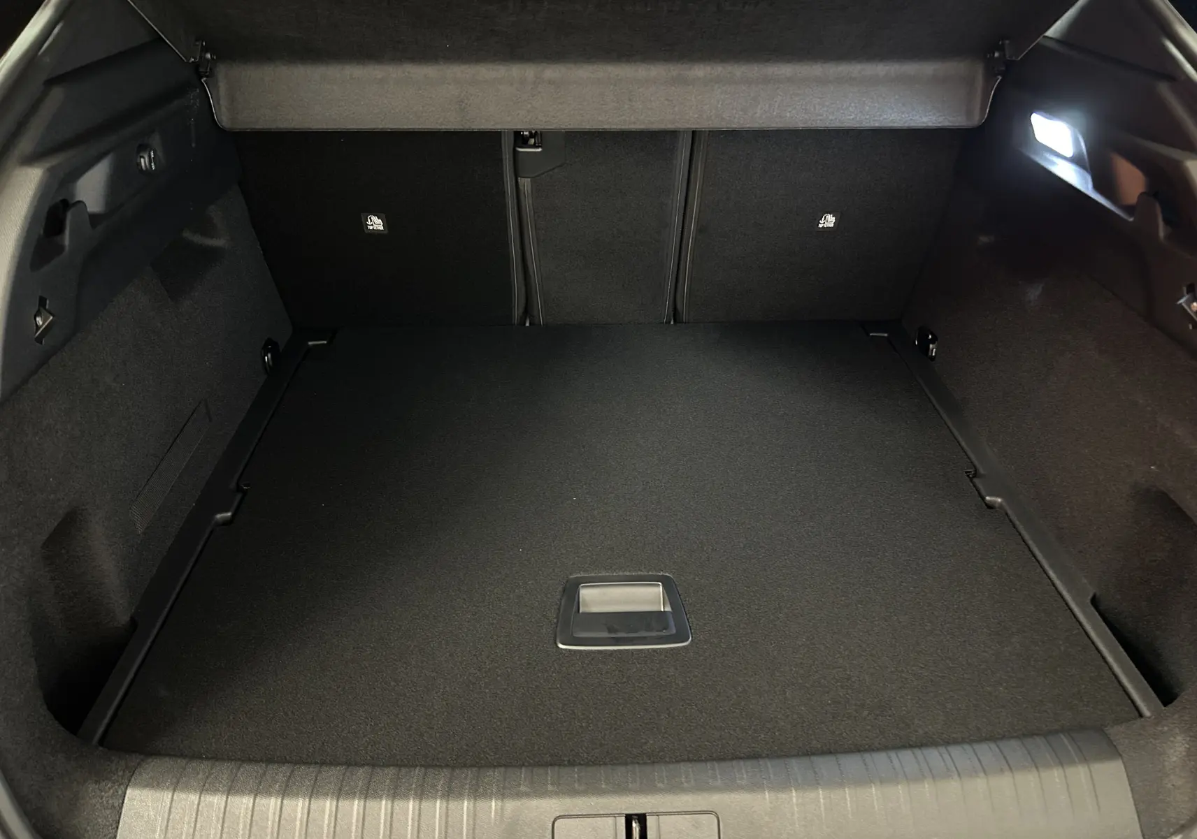 Vue intérieure du coffre spacieux et propre du Peugeot 3008 gris Artense, avec éclairage latéral et plancher plat.
