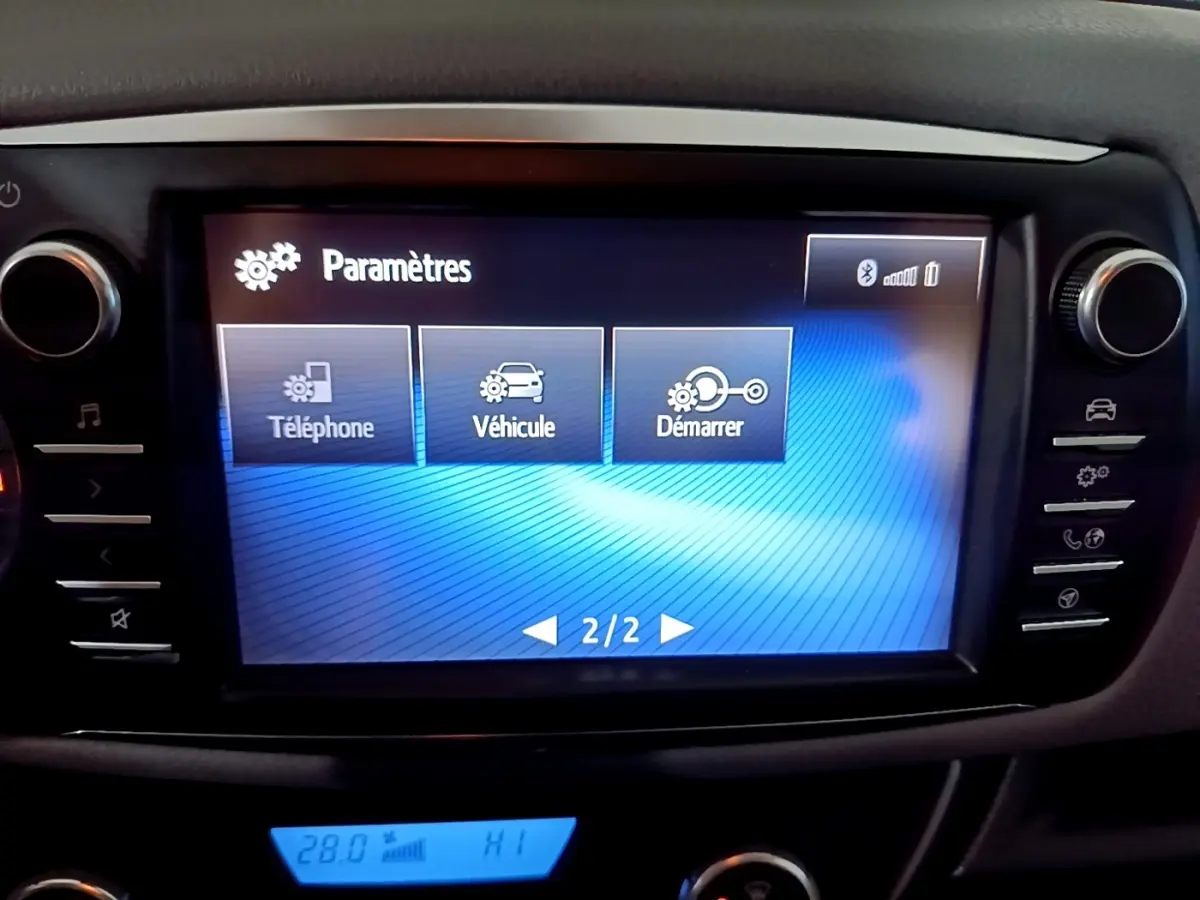 Écran tactile central de la Toyota Yaris blanche 2020 affichant le menu paramètres avec options téléphone, véhicule et démarrer.