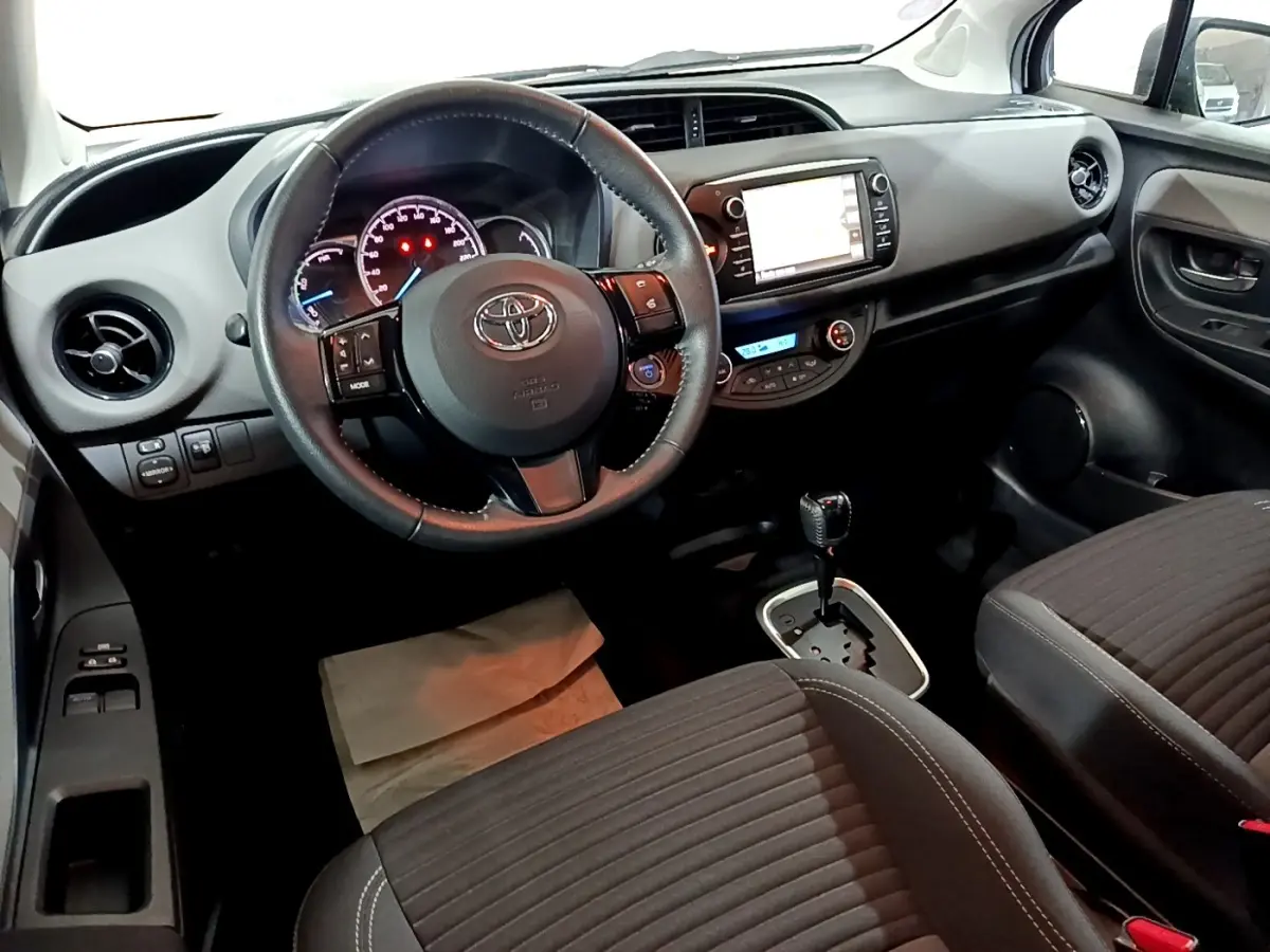 Vue intérieure avant de la Toyota Yaris 1.5 Hybride 2020, volant cuir alu multifonctions et écran tactile central visible.