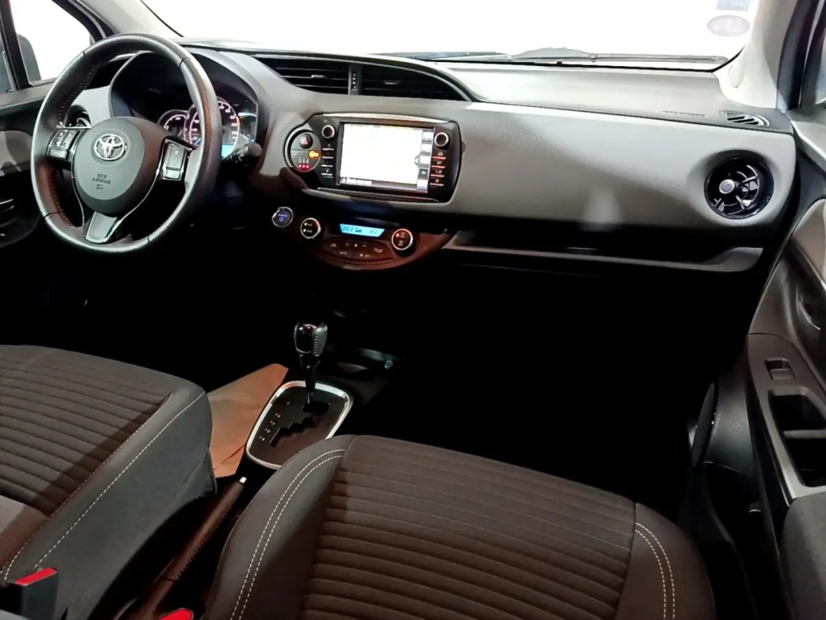 Vue intérieure avant droite de la Toyota Yaris 1.5 Hybride 2020 avec tableau de bord noir et écran tactile central.