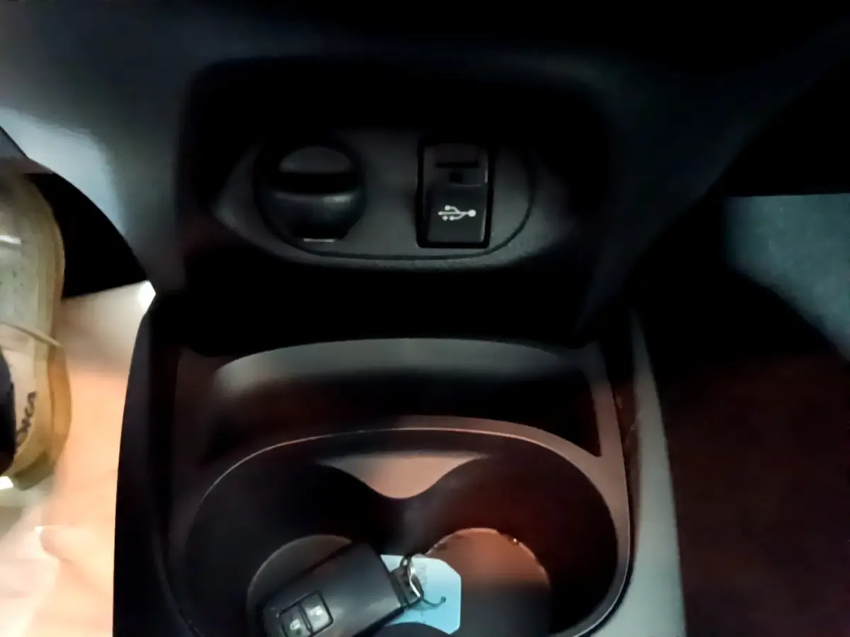 Gros plan sur la console centrale noire de la Toyota Yaris blanche 2020, avec prise USB et porte-gobelets.