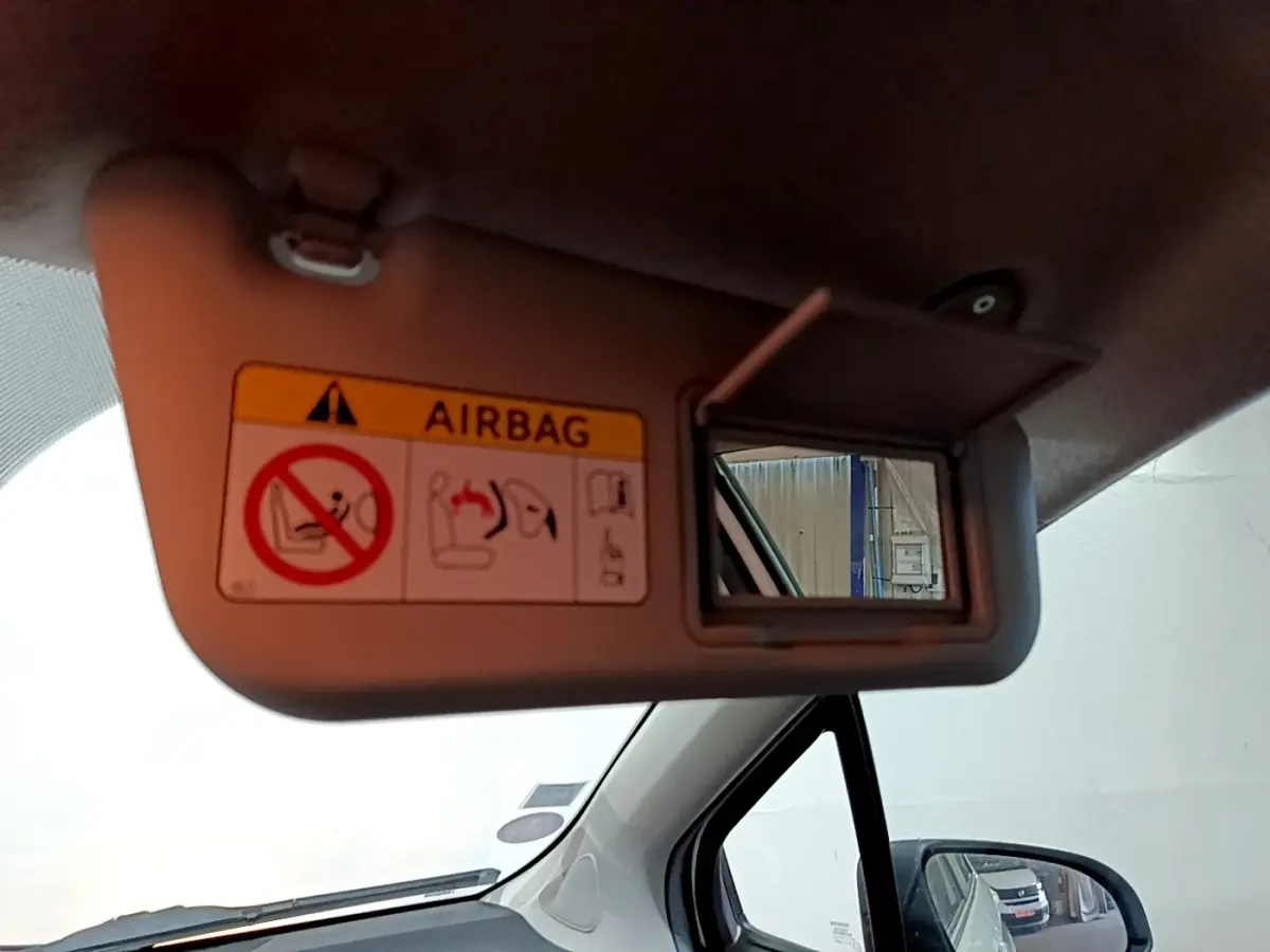 Détail du pare-soleil côté conducteur avec miroir et avertissement airbag dans l’habitacle d’une Toyota Yaris blanche.