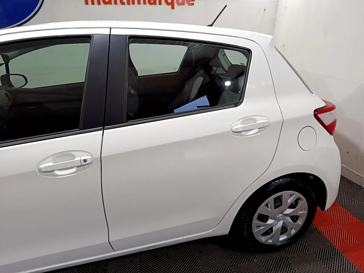 Vue latérale droite d'une Toyota Yaris blanche 2020, mettant en valeur les portes arrière et la roue arrière.