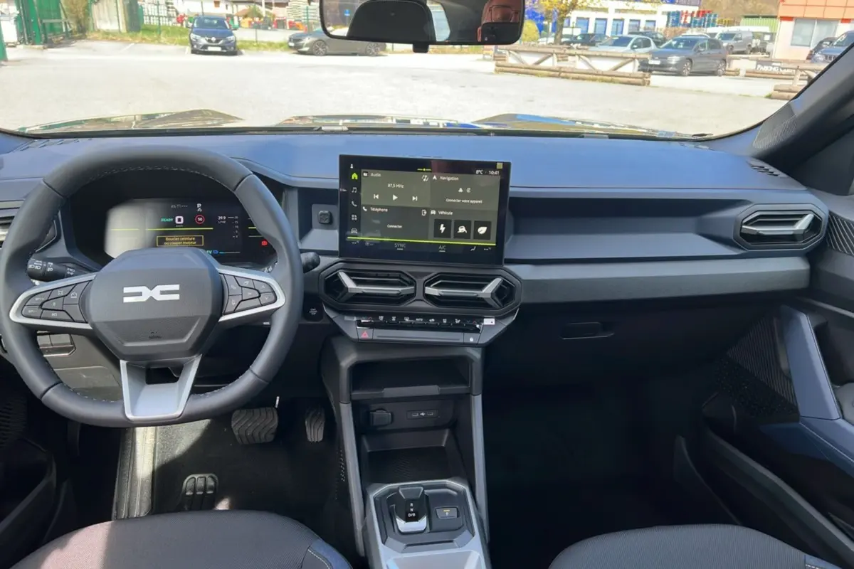 Vue intérieure avant du tableau de bord et volant cuir du Dacia Bigster Hybrid 155 Expression Plus, avec écran tactile central.