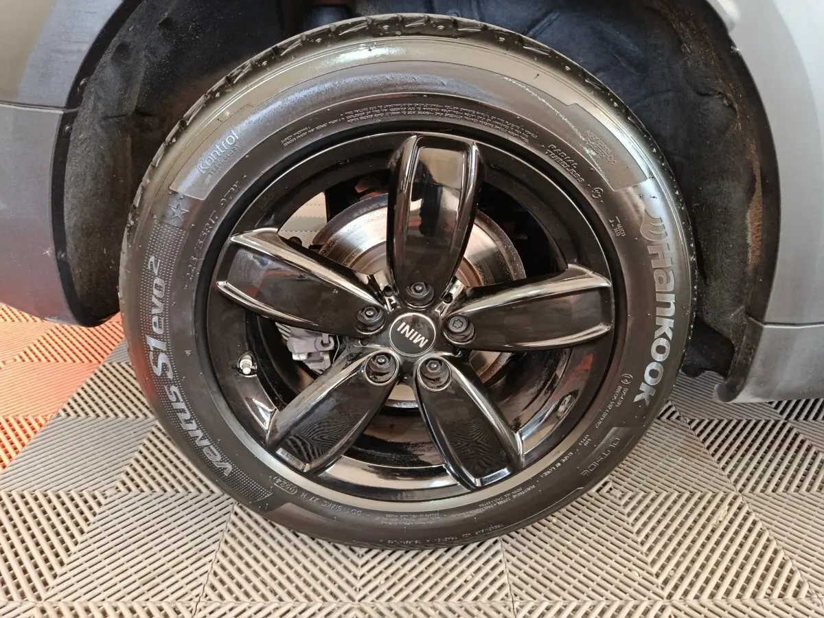 Gros plan sur la jante noire brillante en cinq branches du MINI Countryman gris foncé, avec pneu Hankook visible.
