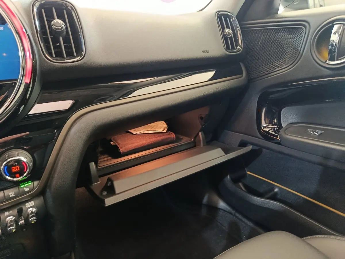 Intérieur du MINI Countryman Cooper 2023, vue côté passager sur boîte à gants ouverte avec tableau de bord noir brillant.