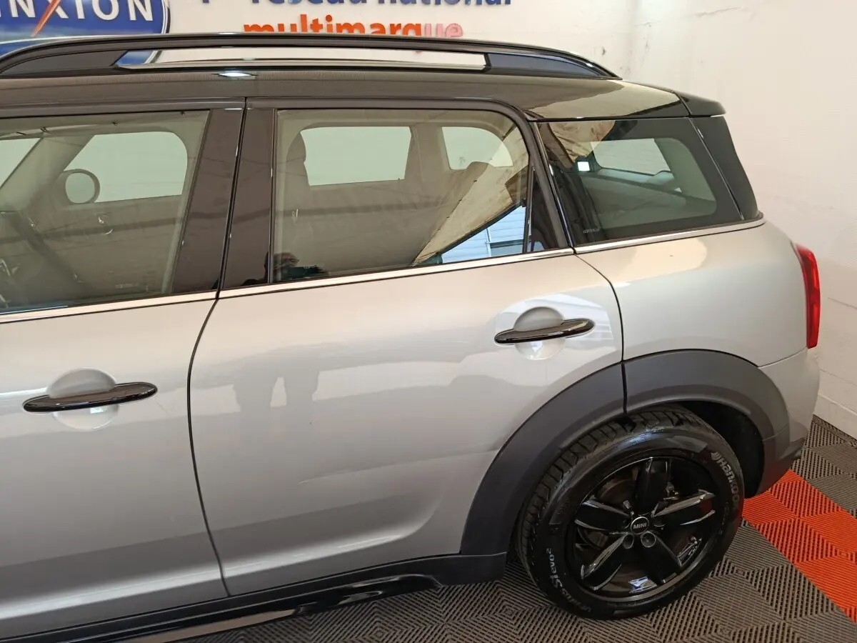 Vue latérale droite sur l'arrière d'une MINI Countryman gris foncé avec toit noir et jantes noires brillantes.