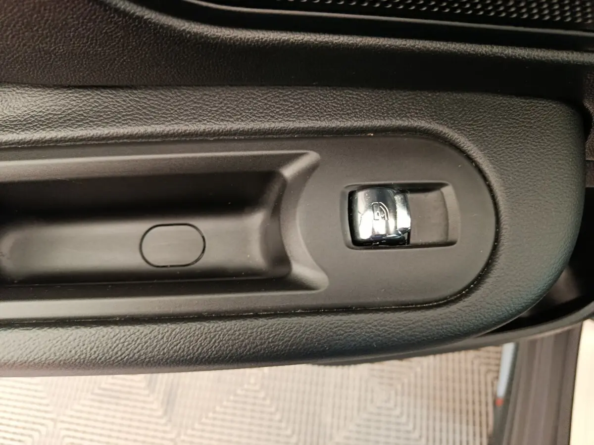 Gros plan sur la commande de verrouillage des portes côté conducteur, finition noire mate et chrome, MINI Countryman gris foncé.
