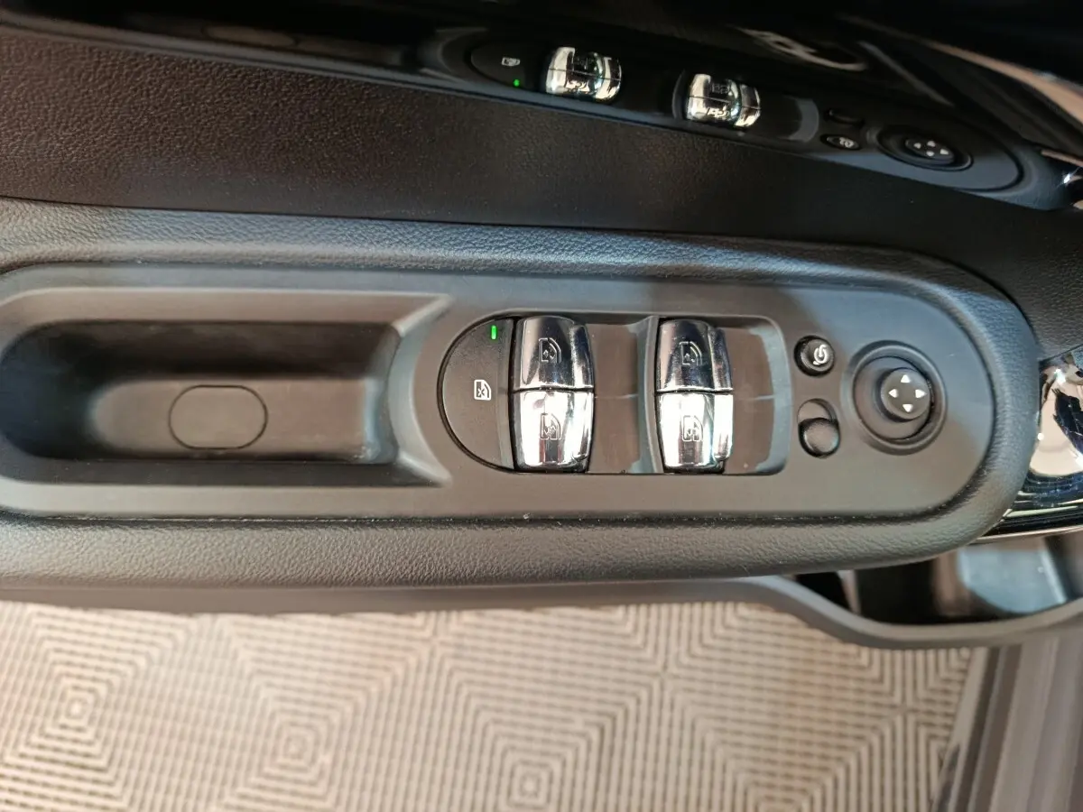 Gros plan sur les commandes des vitres et rétroviseurs côté conducteur du MINI Countryman gris foncé 2023.
