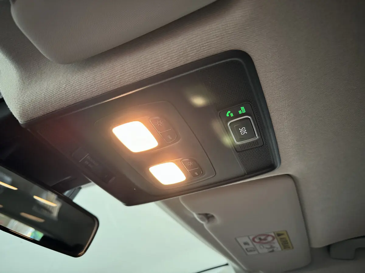 Plafonnier intérieur allumé avec bouton SOS dans une Renault Clio gris clair, vue du pare-brise vers le plafond.