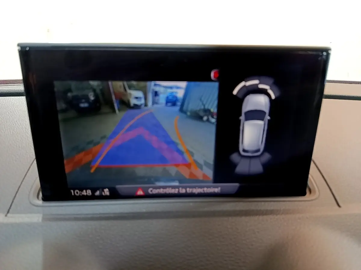 Écran intérieur affichant la caméra de recul et les capteurs de stationnement de l'Audi A3 gris foncé, vue du tableau de bord.