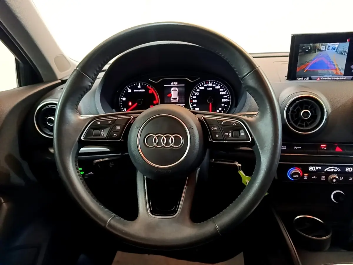 Vue frontale du volant cuir multifonctions noir de l'Audi A3 30 TDI 116 S tronic Business Line avec tableau de bord et écran multimédia.