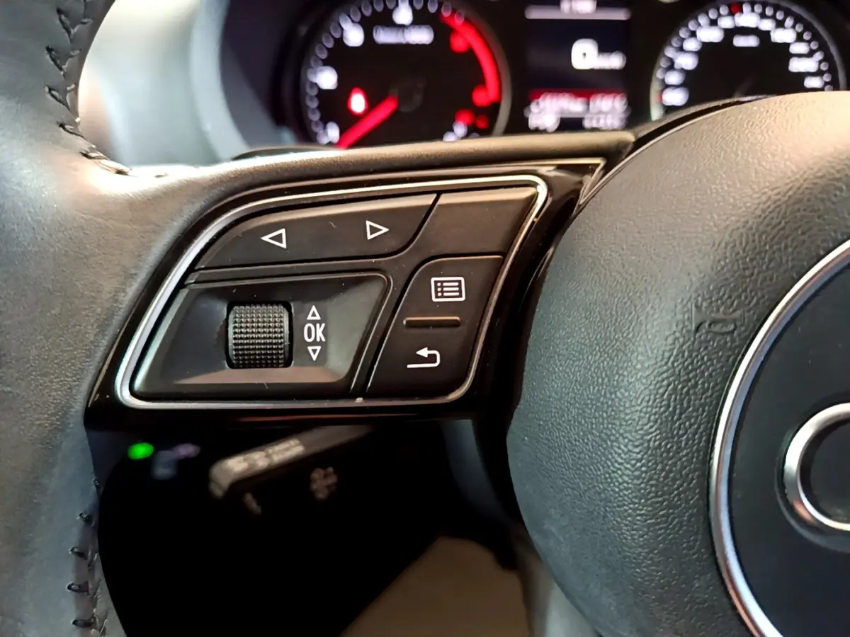 Gros plan sur le côté gauche du volant cuir noir de l'Audi A3 30 TDI 2019 avec commandes multifonctions.