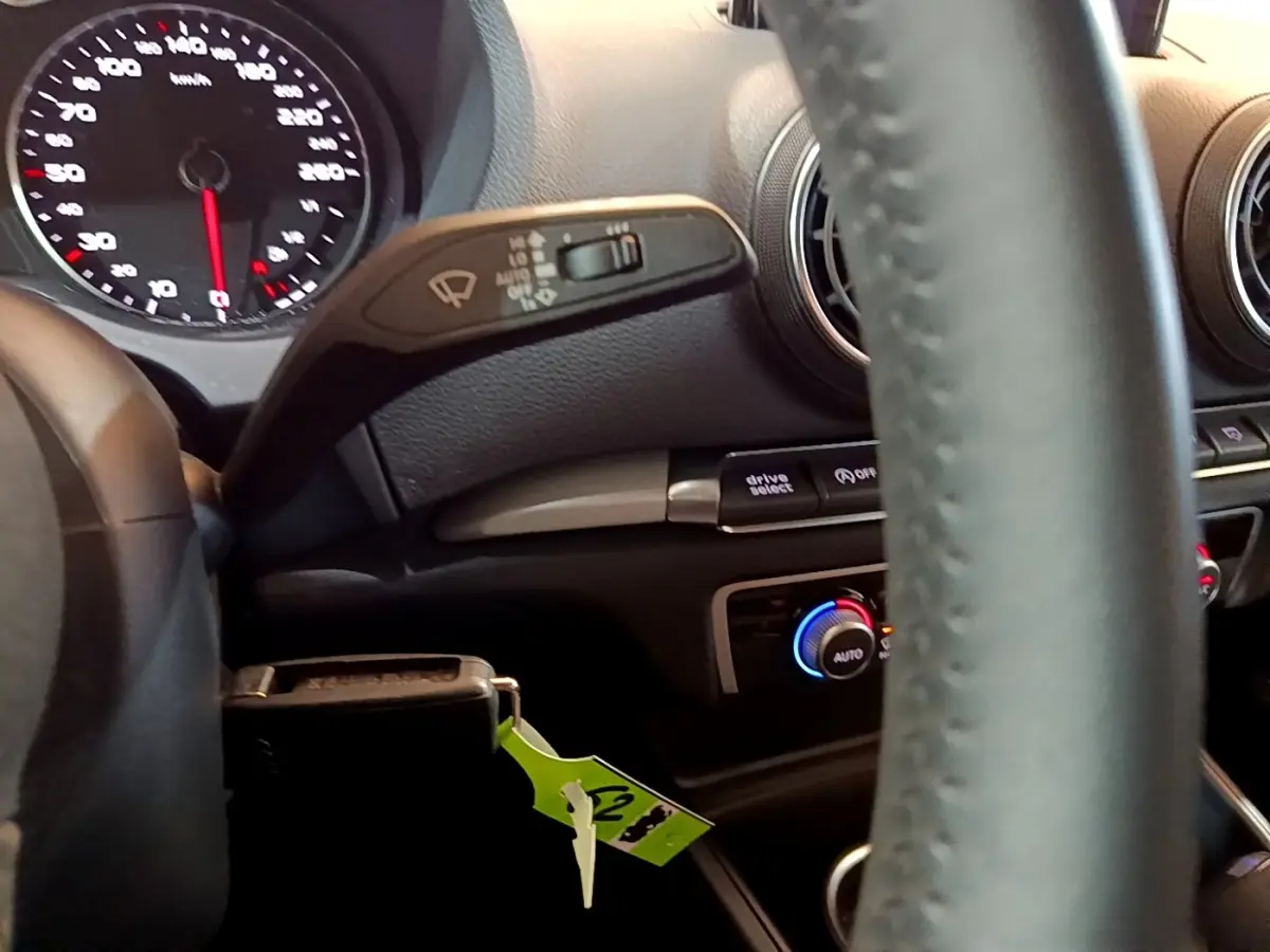 Vue intérieure centrée sur le volant cuir et la commande de climatisation bicolore d'une Audi A3 gris foncé 2019.