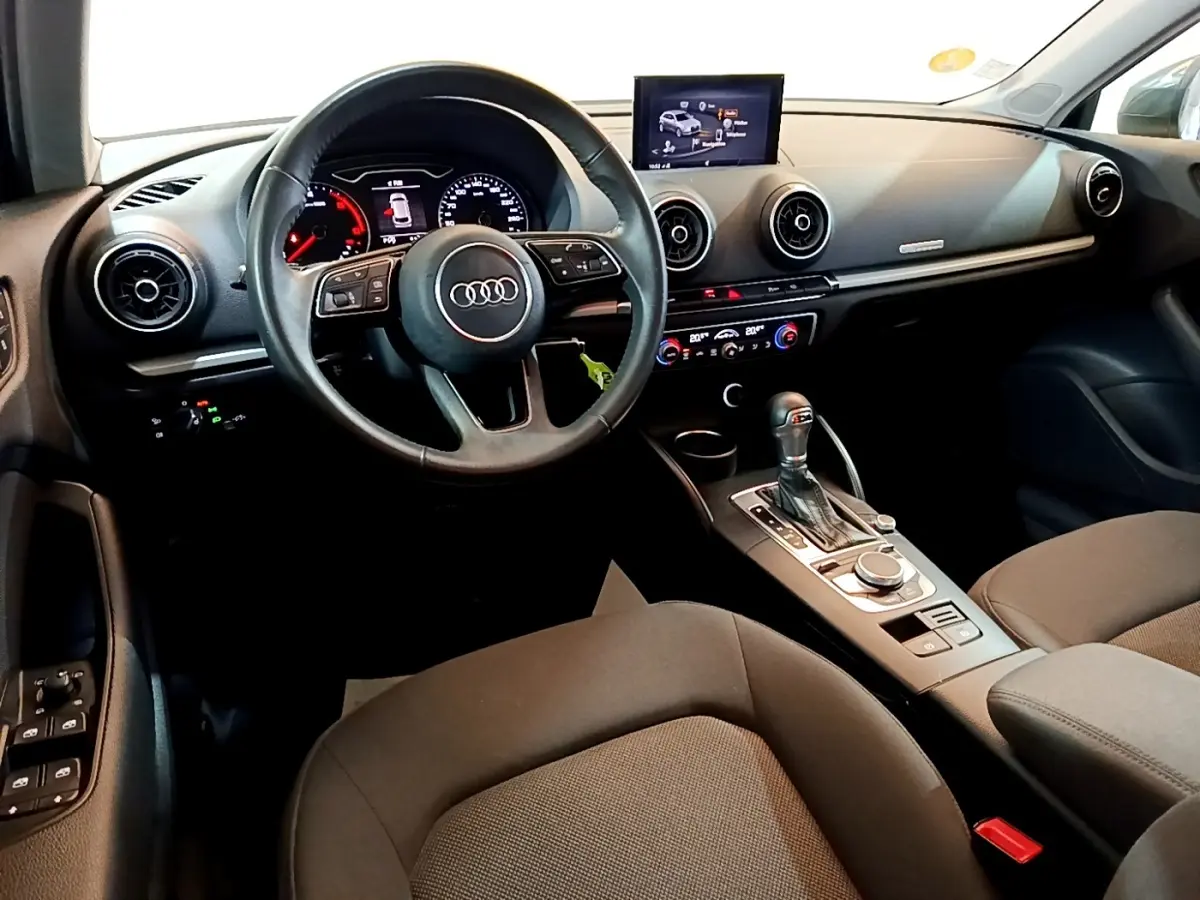 Vue intérieure de l'Audi A3 2019, tableau de bord et volant cuir multifonctions en noir, avec écran central et console automatique.