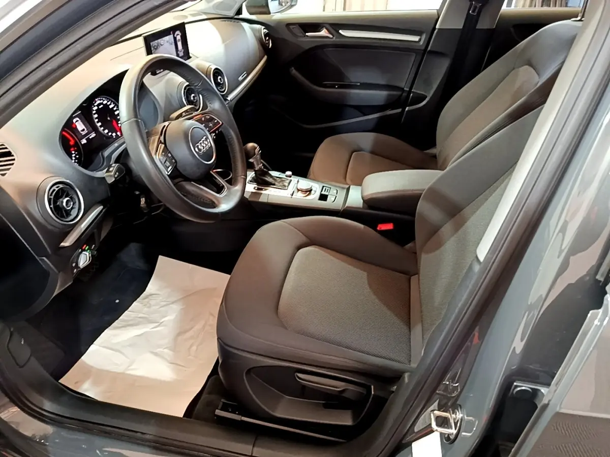 Vue intérieure côté conducteur de l'Audi A3 30 TDI 2019 gris foncé, volant cuir multifonctions et tableau de bord digital.