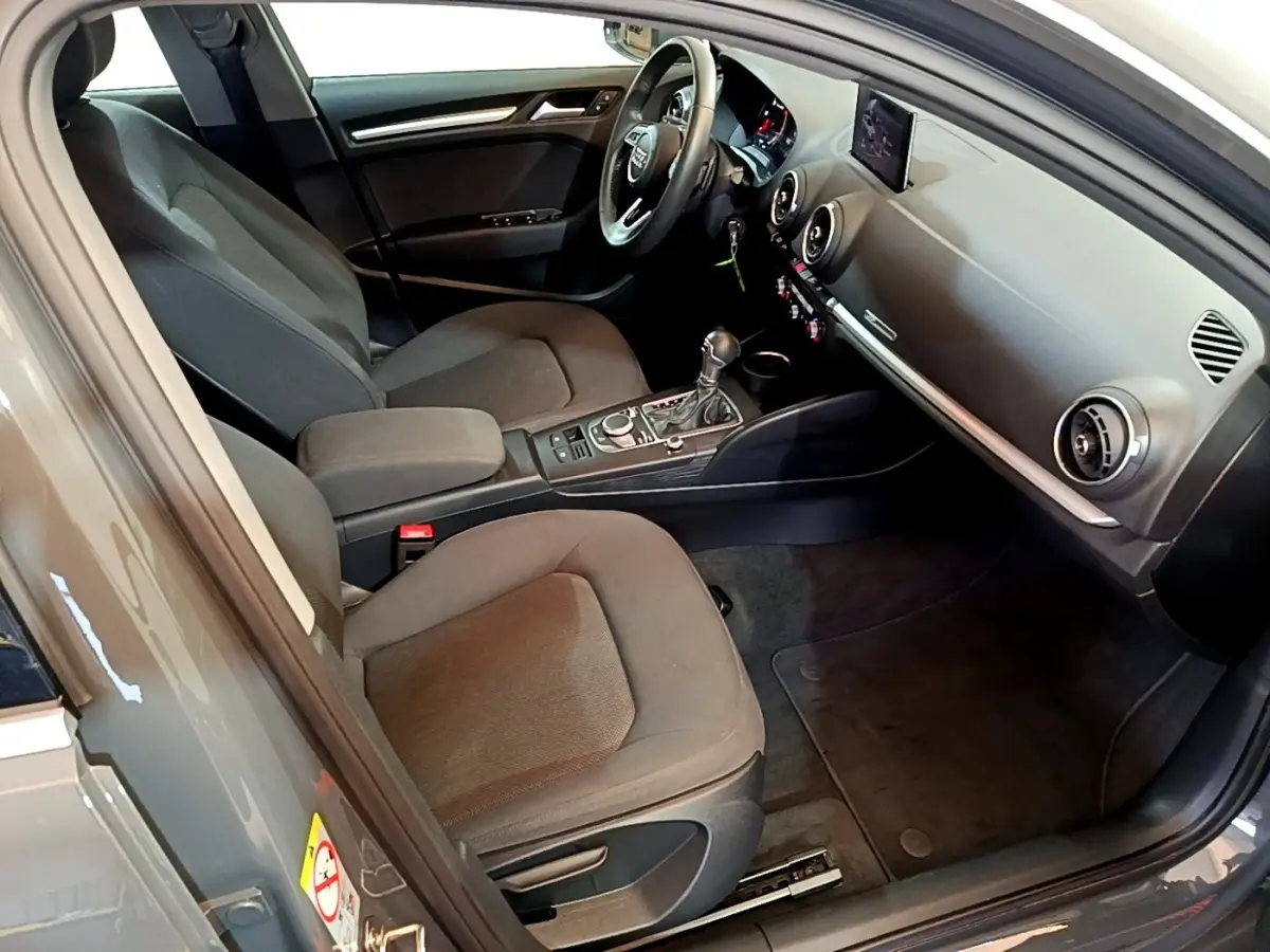 Vue intérieure côté conducteur de l'Audi A3 30 TDI 2019 gris foncé, avec volant cuir multifonctions et tableau de bord digital.