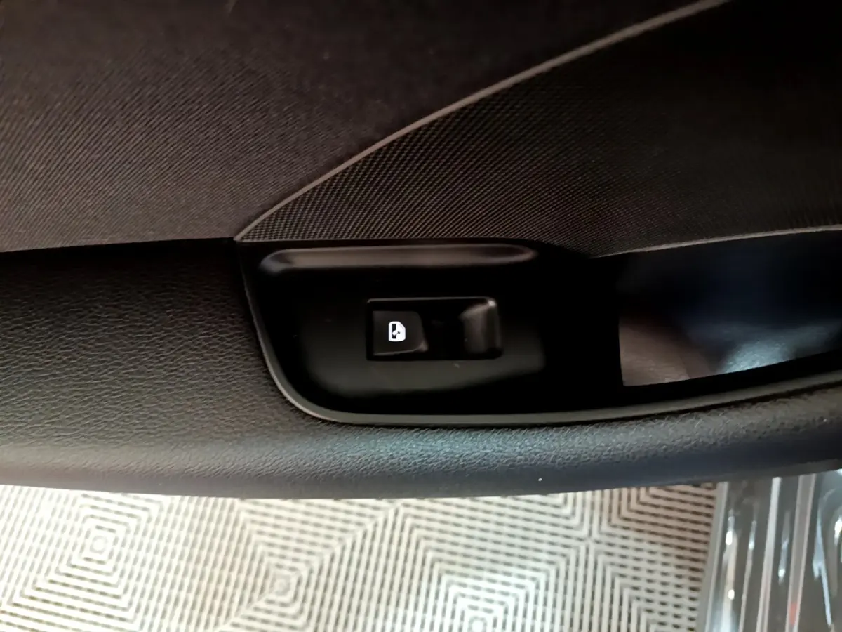 Gros plan sur le bouton de verrouillage des portes dans la portière intérieure côté conducteur de l'Audi A3 gris foncé.