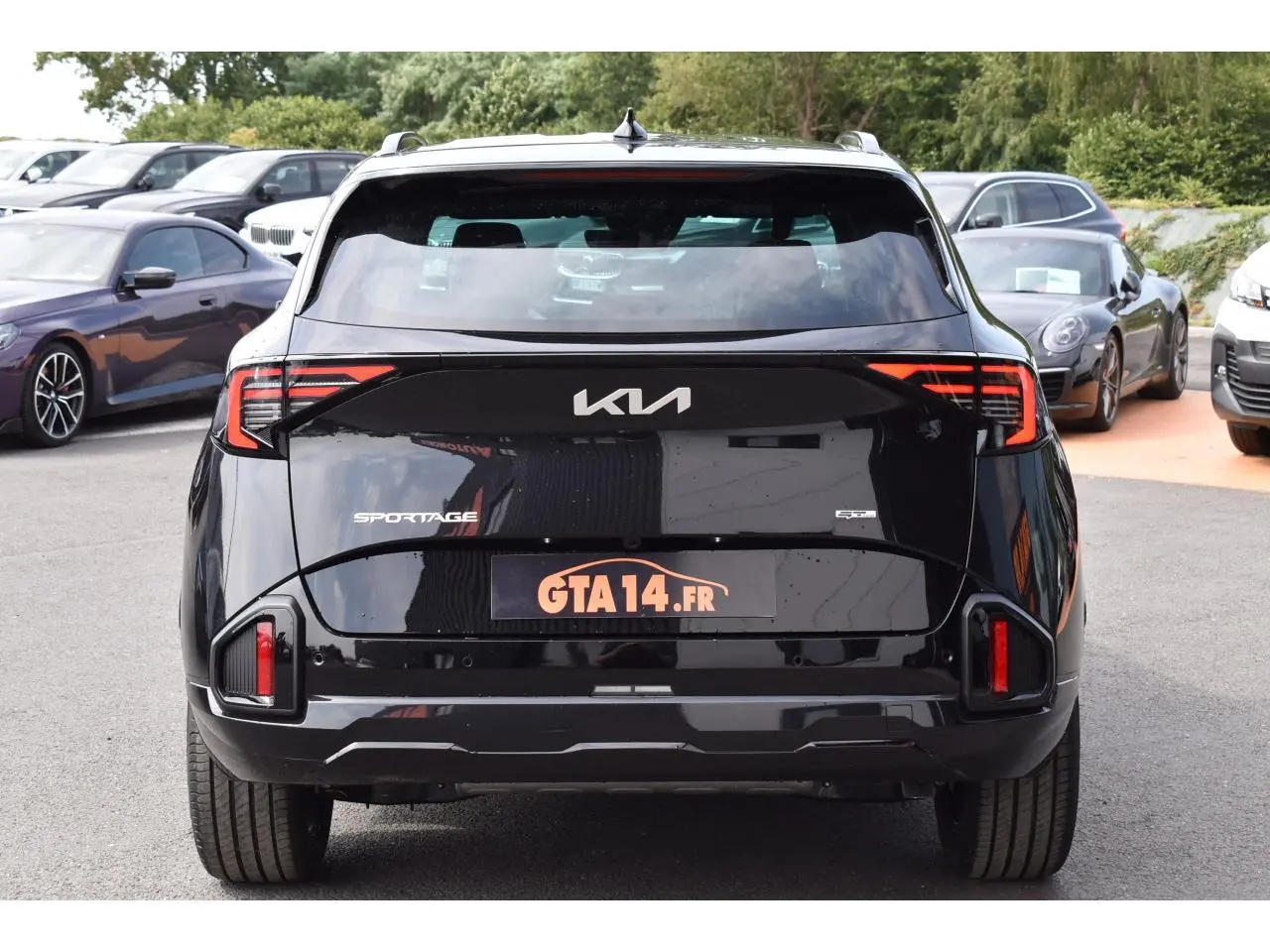 Vue arrière d'un Kia Sportage noir 2026 avec feux arrière LED et logo KIA visible sur un parking.