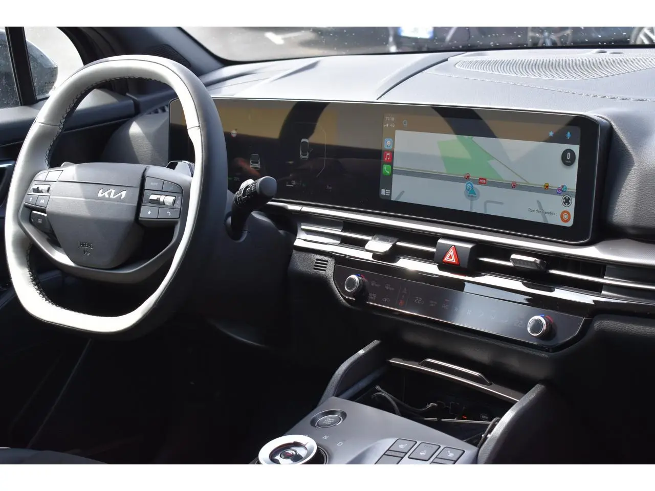 Vue intérieure du tableau de bord du Kia Sportage hybride 2026, avec écran tactile large et volant multifonction noir.