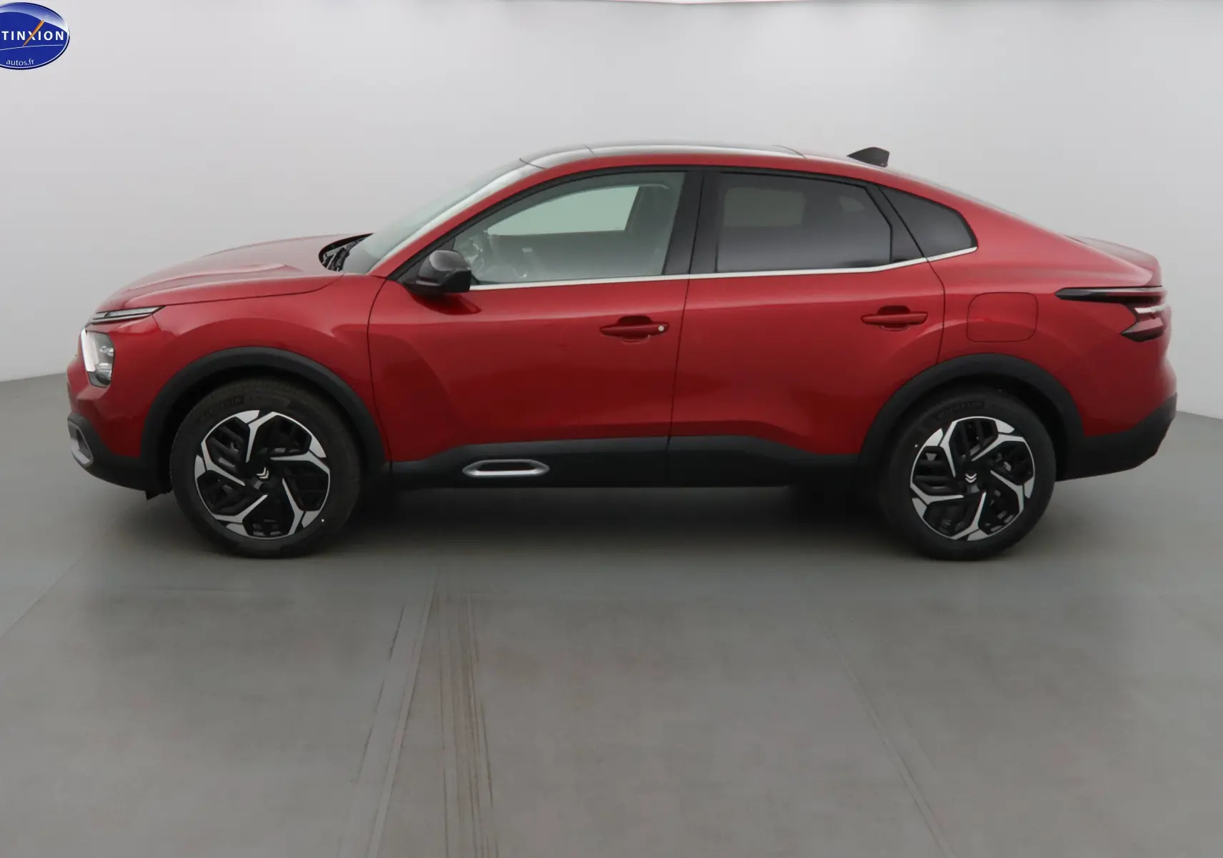 Profil côté gauche d'une Citroën C4 X rouge Elixir Métal 2023 avec jantes noires et toit noir contrasté.