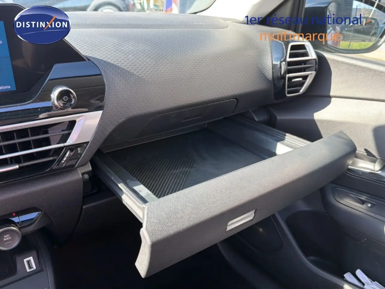 Vue intérieure côté passager du tableau de bord de la Citroën C4 X 2023 avec boîte à gants ouverte et finition noire.