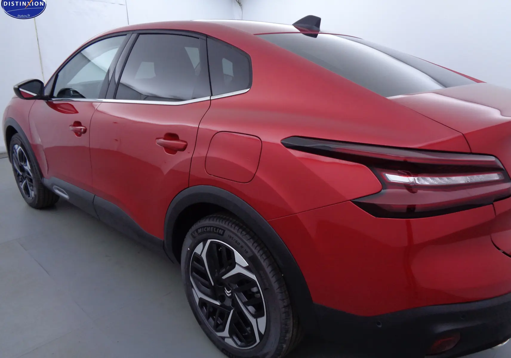 Vue 3/4 arrière droite d'une Citroën C4 X rouge Elixir métal avec feux arrière LED et jantes bicolores.