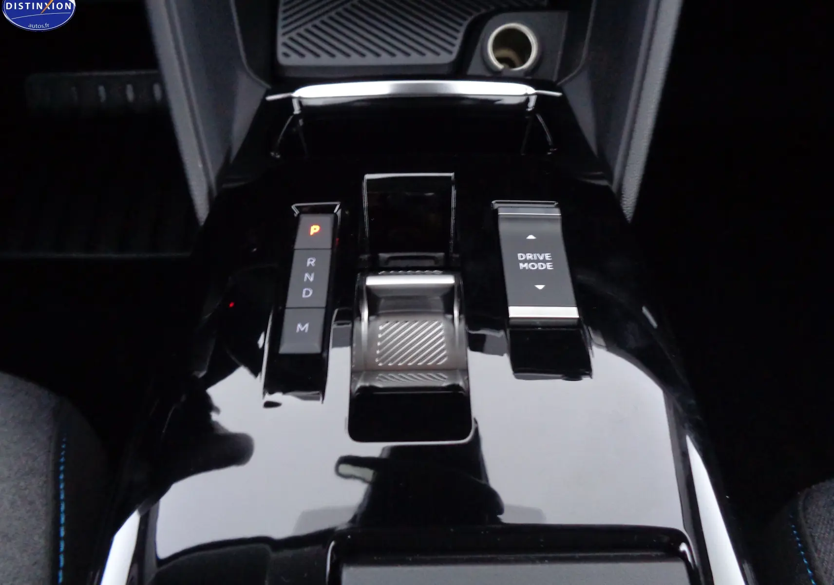 Gros plan sur la console centrale noire brillante de la Citroën C4 X 2023 avec sélecteur de boîte auto et bouton Drive Mode.