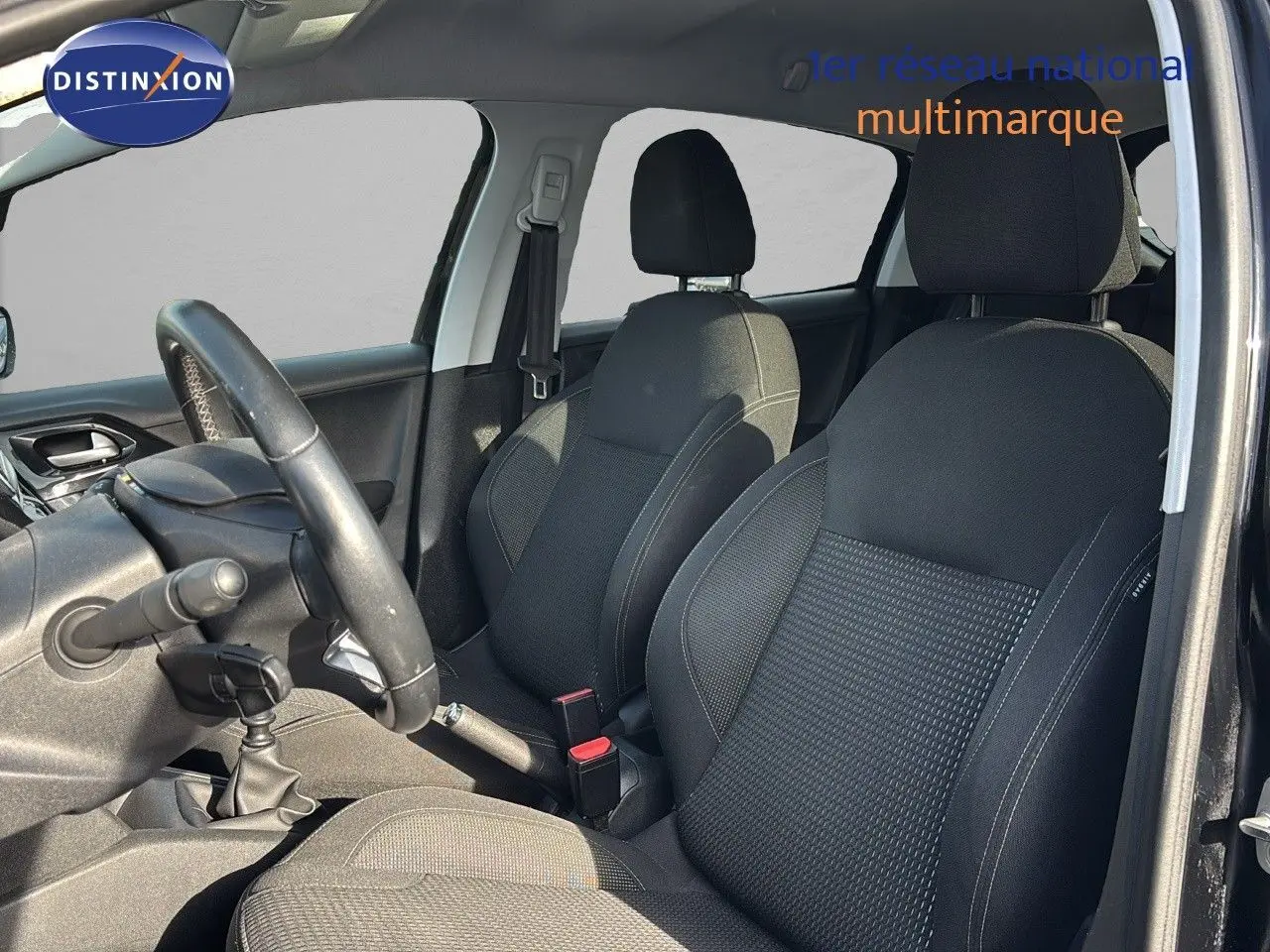 Intérieur avant de la Peugeot 208 noire perle métal, vue côté conducteur montrant les sièges et le volant.