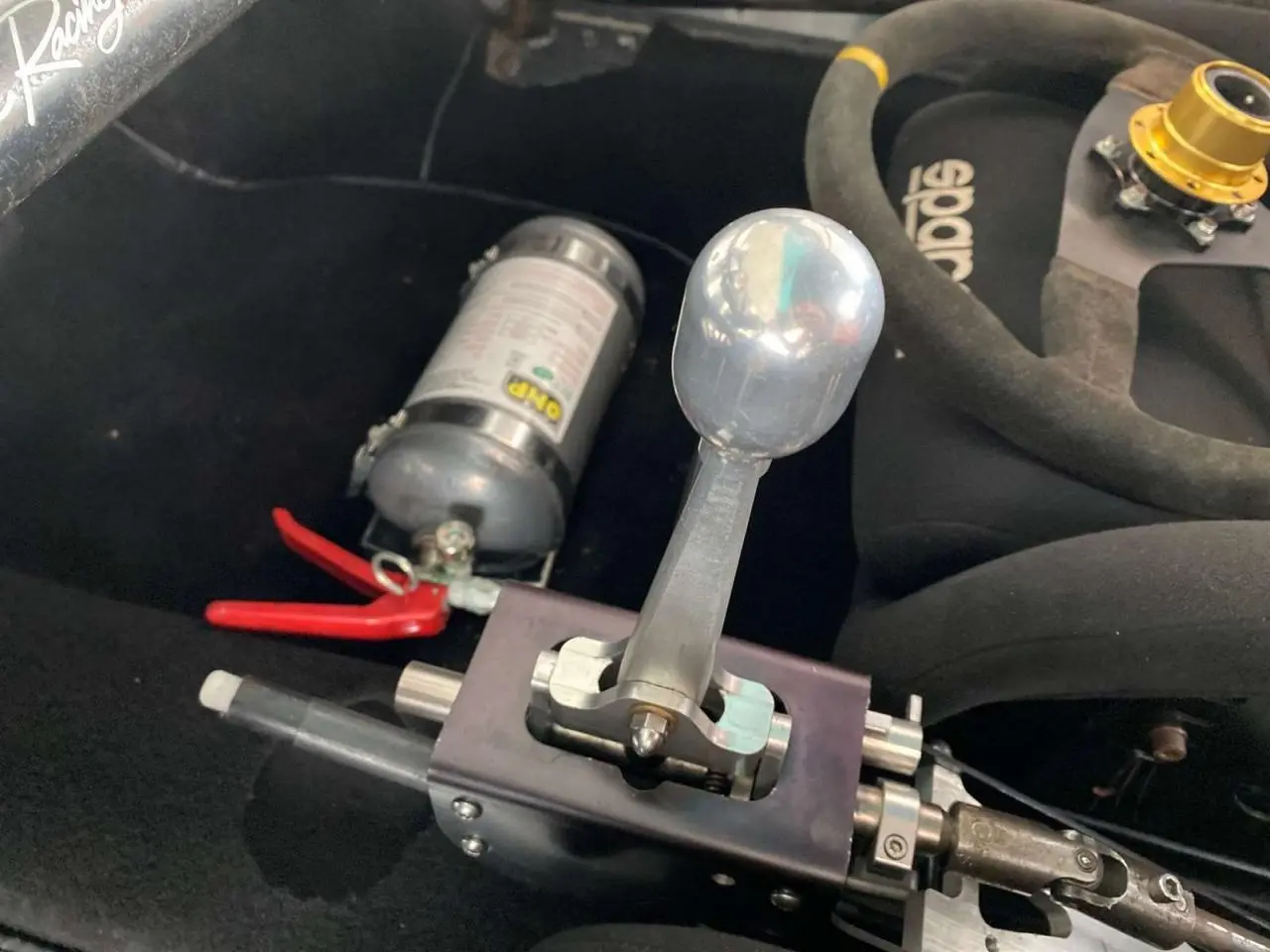 Gros plan sur le levier de vitesse manuel rigide et extincteur dans l'habitacle d'une Porsche 911 3.0 SC gris métallisé.