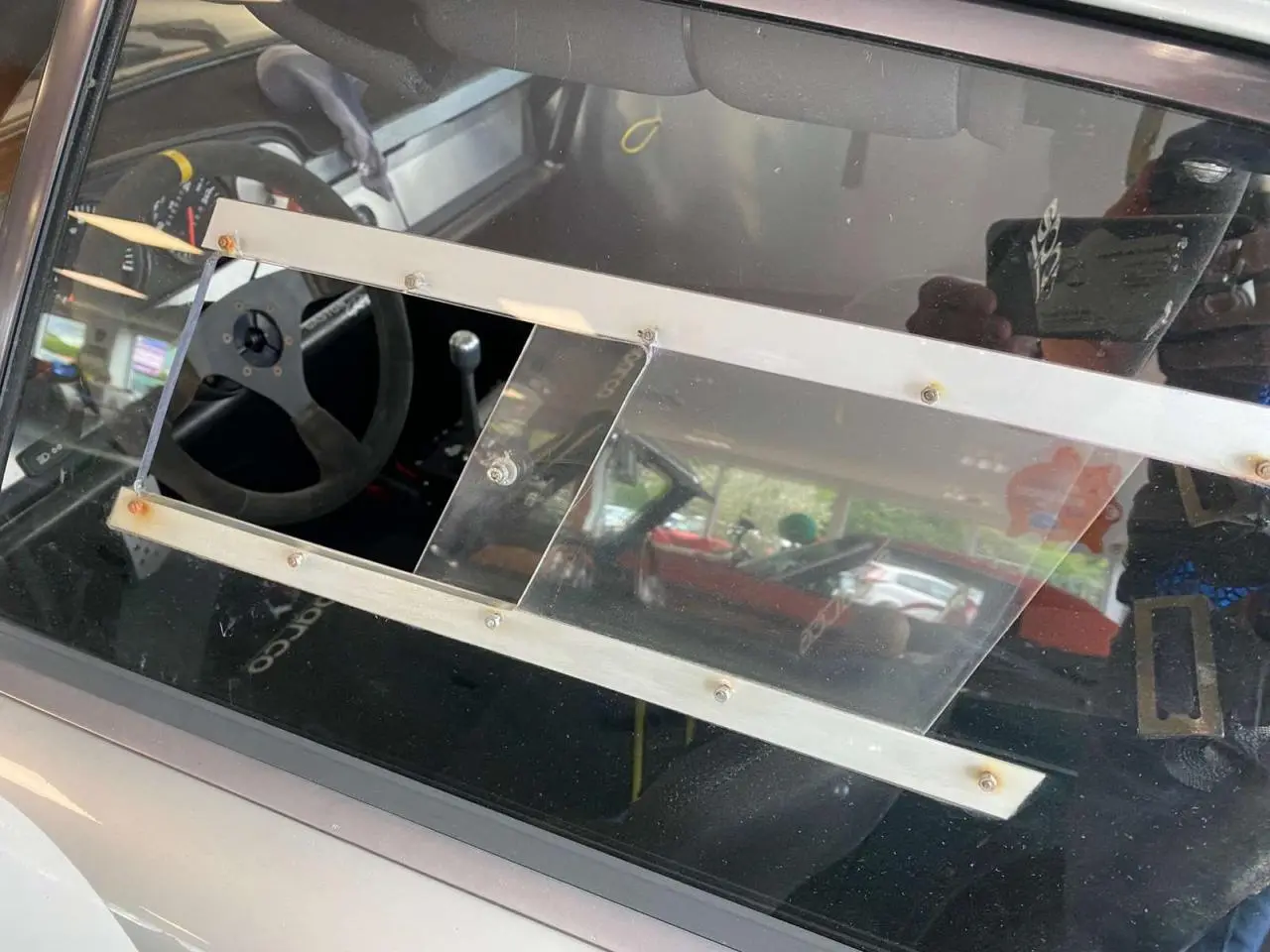 Vue latérale gauche de la Porsche 911 3.0 SC gris métallisé avec vitre latérale en Lexan et intérieur course Sparco visible