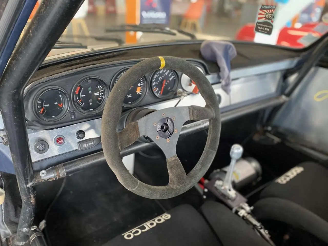 Intérieur de Porsche 911 3.0 SC 1980 vu côté conducteur, volant Sparco, arceau tubulaire et baquets course noirs.