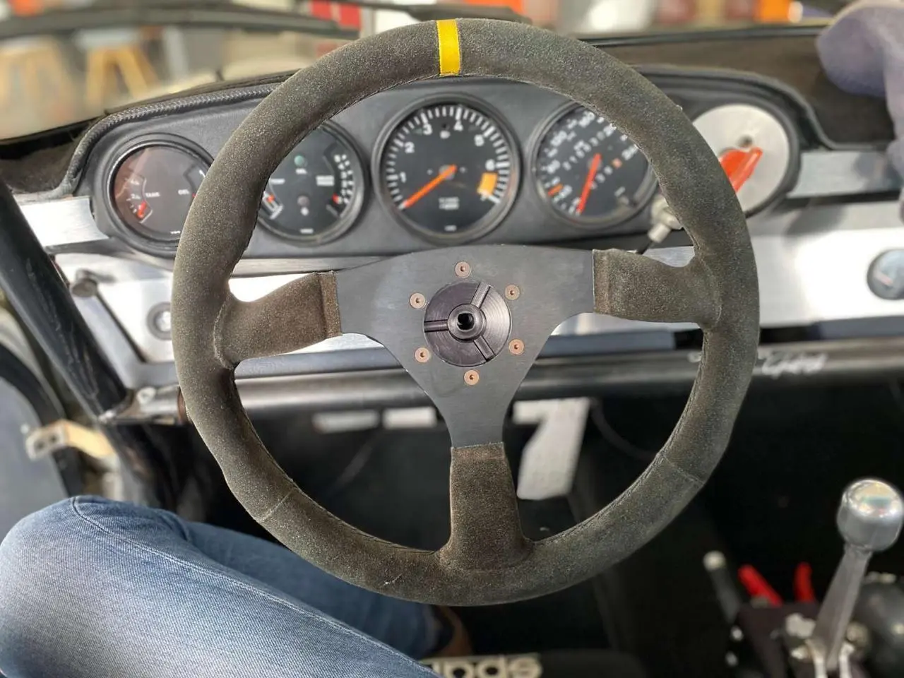 Volant Sparco en alcantara avec moyeu débrayable, tableau de bord et compteurs d'une Porsche 911 3.0 SC gris métallisé vue de l'intérieur.