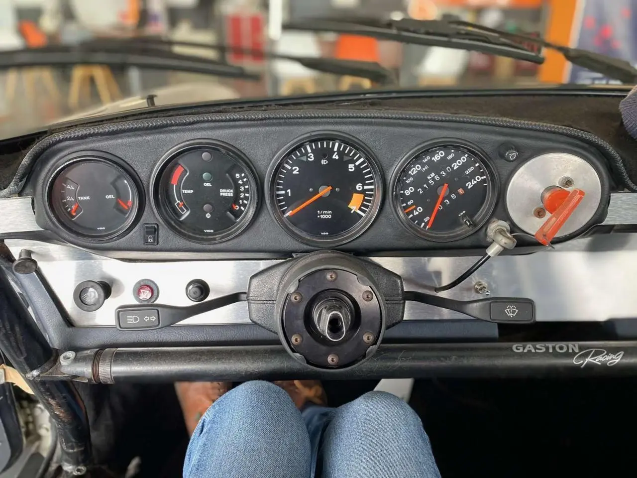 Tableau de bord en aluminium brossé d'une Porsche 911 3.0 SC 1980, avec compteurs ronds et arceau de sécurité visible.