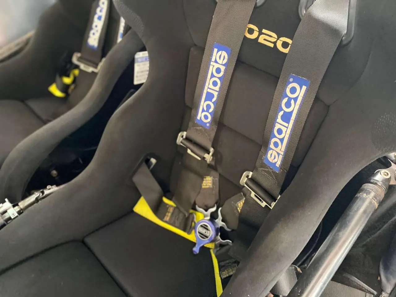 Gros plan sur les baquets noirs Sparco avec harnais 6 points dans une Porsche 911 3.0 SC gris métallisé de 1980.