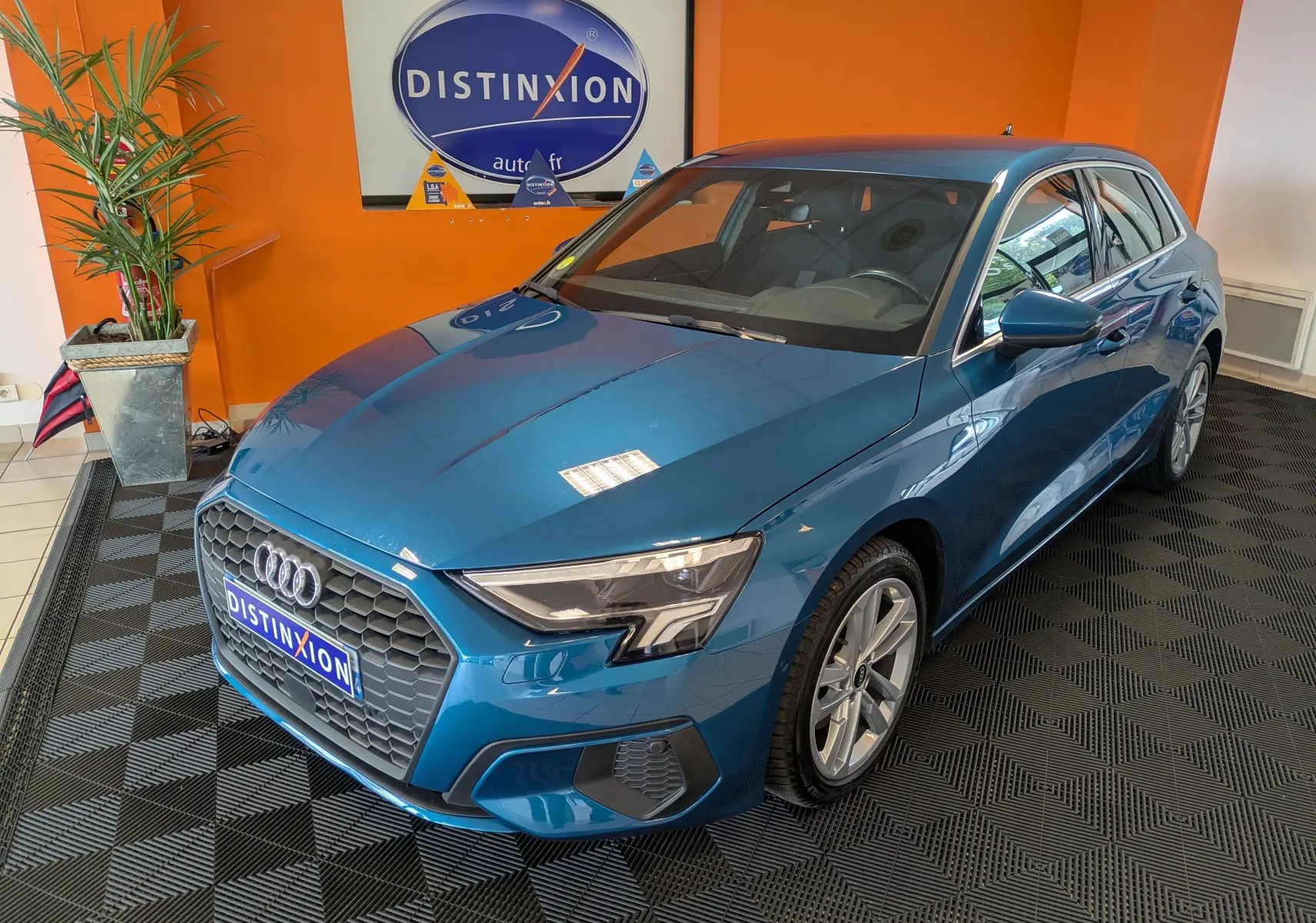 Audi A3 Sportback bleu Atollblau en 3/4 avant droit, avec calandre hexagonale et jantes alliage 17 pouces visibles.