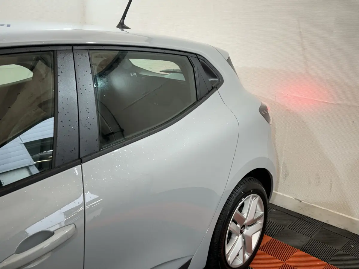 Vue arrière côté droit de la Renault Clio gris clair 2025, avec jante alliage et antenne de toit visible.