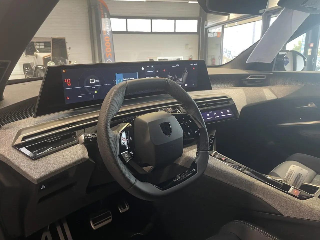 Vue intérieure côté conducteur du Peugeot 3008 GT 2025, volant compact noir et tableau de bord numérique panoramique.