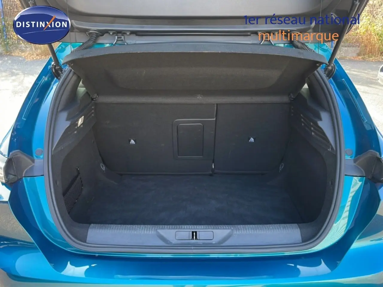Coffre ouvert d'une Peugeot 308 1.2 PureTech 130ch Allure bleu obsession métal, vue arrière montrant l'espace de chargement vide.