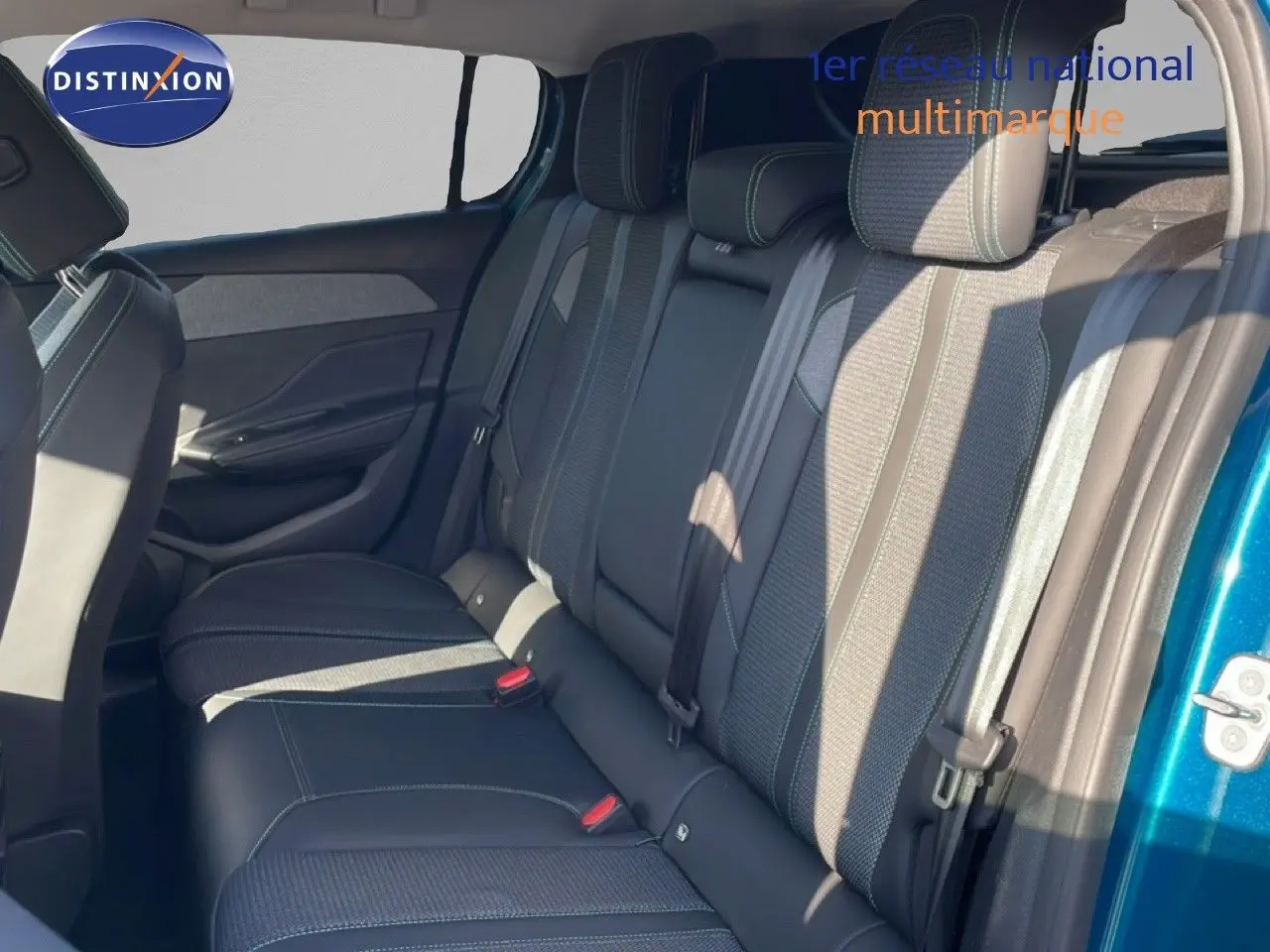 Vue latérale droite de l'intérieur arrière de la Peugeot 308 2024, sièges tissu et cuir gris avec surpiqûres contrastantes.